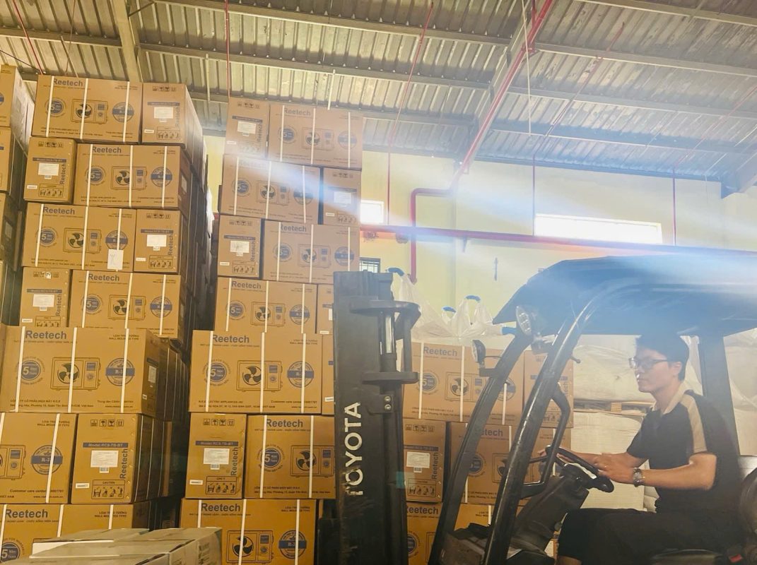 Nhân viên lái xe nâng di chuyển máy lạnh trong kho