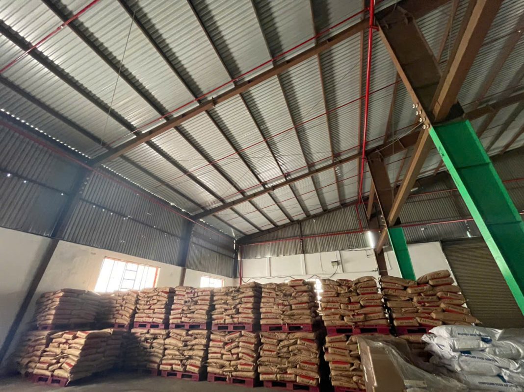 Không gian bên trong nhà kho chuyên nghiệp với các bao hàng được xếp trên pallet và có hệ thống phòng cháy chữa cháy.